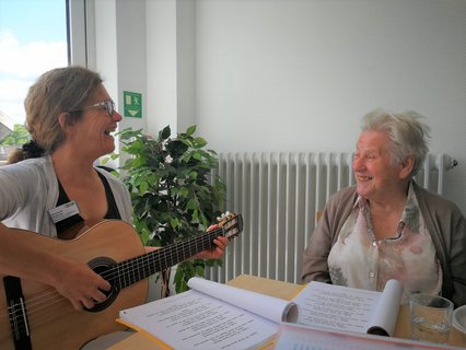 Bild zeigt Frau mit Gitarre und eine Patientin